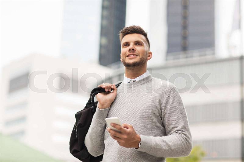 Business, technology, communication and people concept - happy smiling young man in with bag and smartphone on city street, stock photo