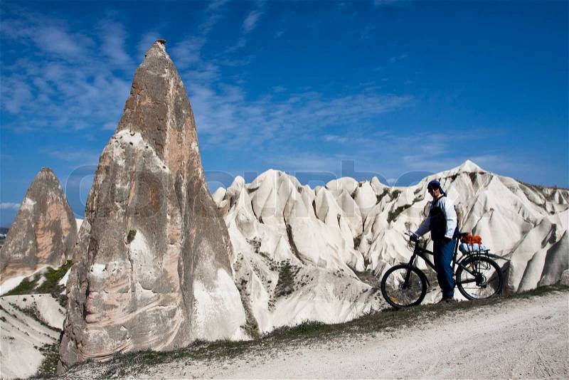 Man riding a bike near the strange stone formations in Cappadocia, Turkey, stock photo