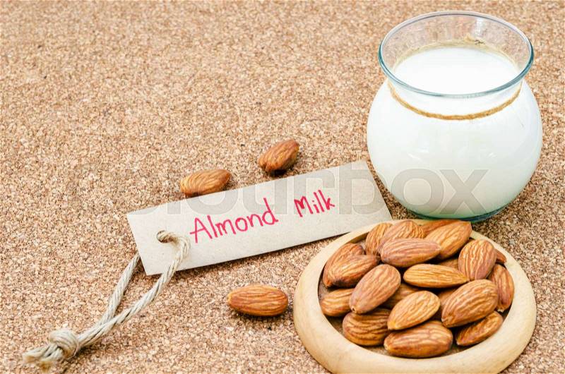 Almond and almond milk in glass with almond tag on wood background.\\ , stock photo
