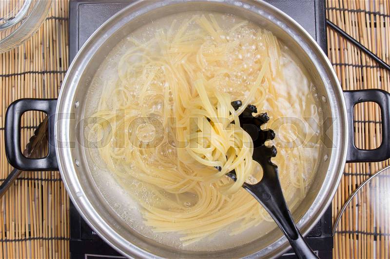 Spaghetti boiling in pan on electric stove / cooking spicy spaghetti concept, stock photo