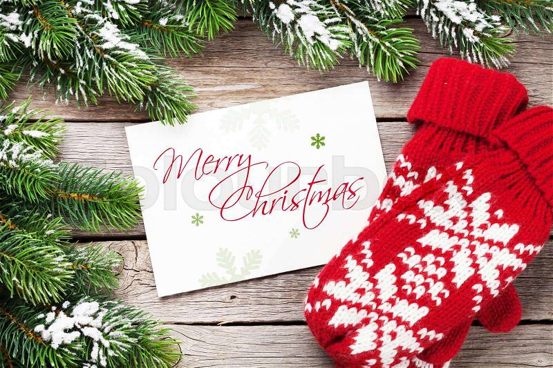 Christmas greeting card, fir tree and mittens on wooden table. Top view with copy space, stock photo