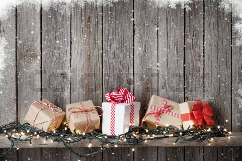 Christmas gift boxes and lights in front of wooden wall with copy space, stock photo