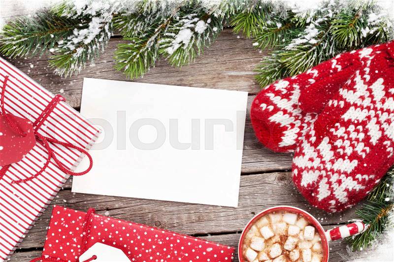 Christmas greeting card, fir tree, mittens, gift boxes and hot chocolate on wooden table. Top view with copy space, stock photo
