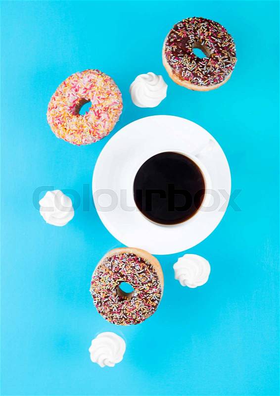 Cup of coffee with donuts and meringues in motion on blue background, stock photo