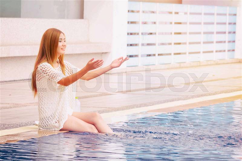 Young Asian woman sitting chill out at swimming pool ,Happy holidays, stock photo