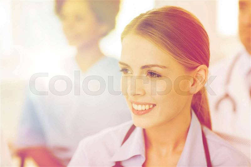 Clinic, profession, people and medicine concept - happy female doctor over group of medics meeting at hospital, stock photo