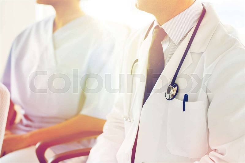 Education, profession, people and medicine concept - close up of happy doctors at seminar or conference in hospital, stock photo