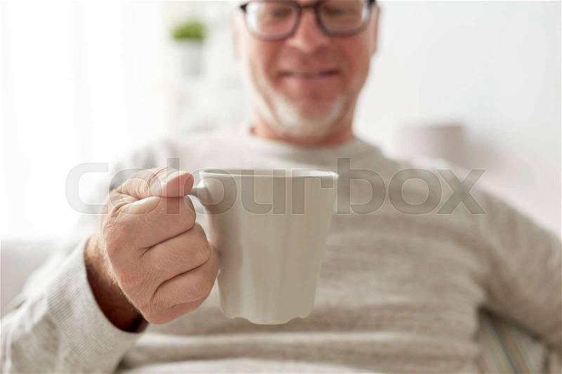 Old age, drink and people concept - happy senior man with cup of tea or coffee at home, stock photo