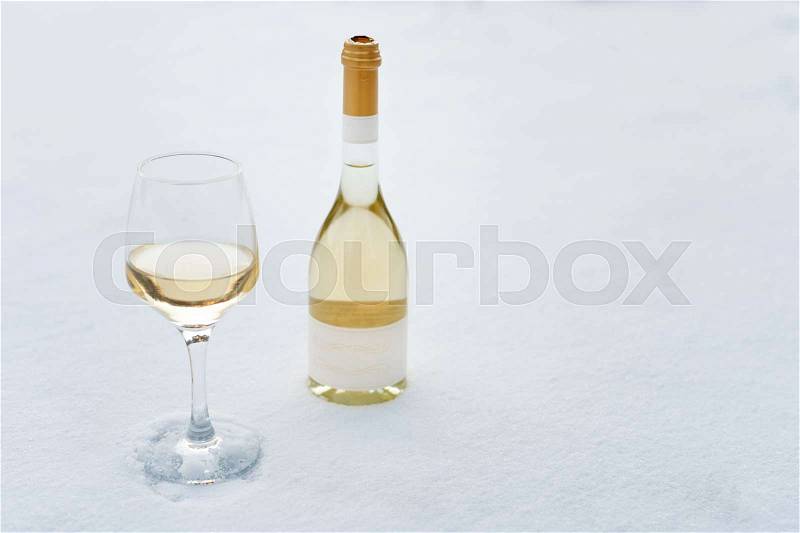 Love, romance, winter holidays, New Year celebration concept. Bottle and glass of white wine chilled by snow, stock photo