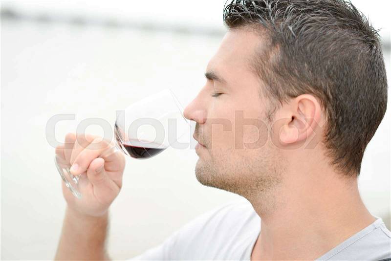 Man smelling a glass of red wine, stock photo