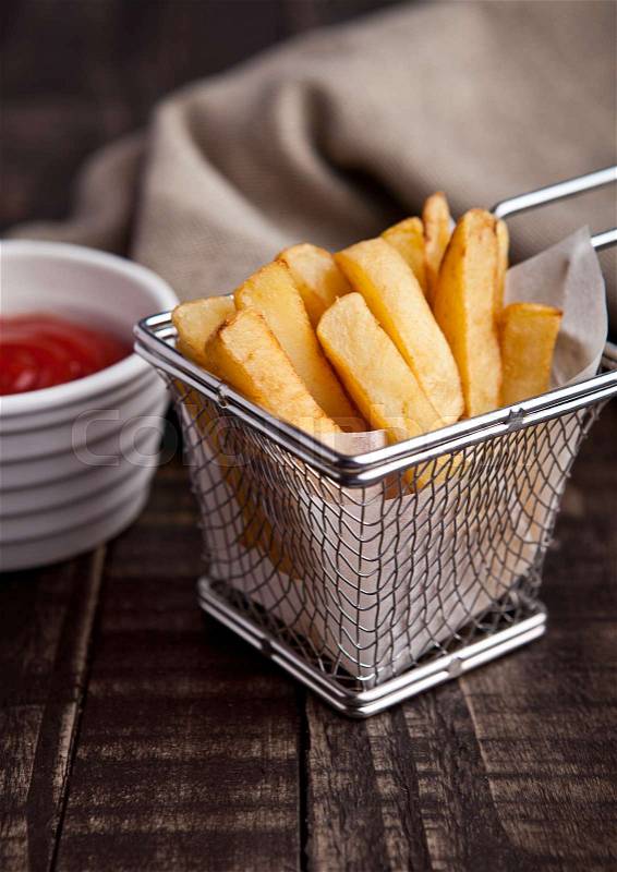 Fried french fries chips in fryer with ketchup on wood. with fresh potatoes and kitchen towel, stock photo