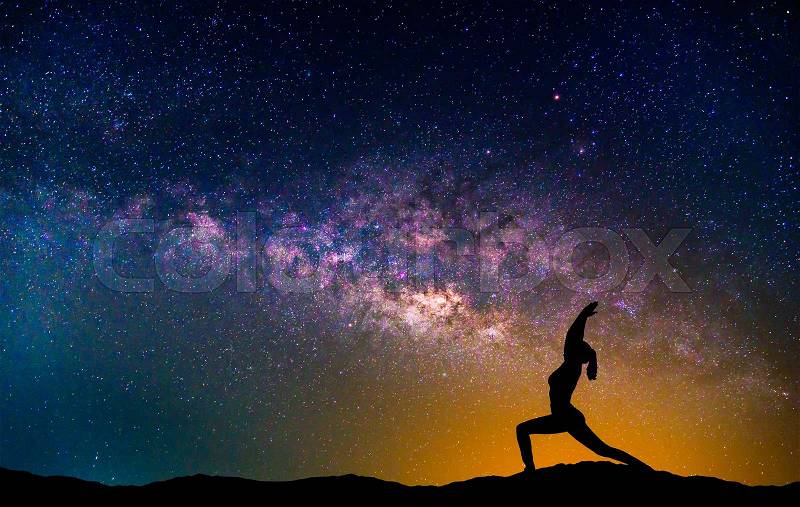 Landscape with Milky way galaxy. Night sky with stars and silhouette woman practicing yoga on the mountain, stock photo
