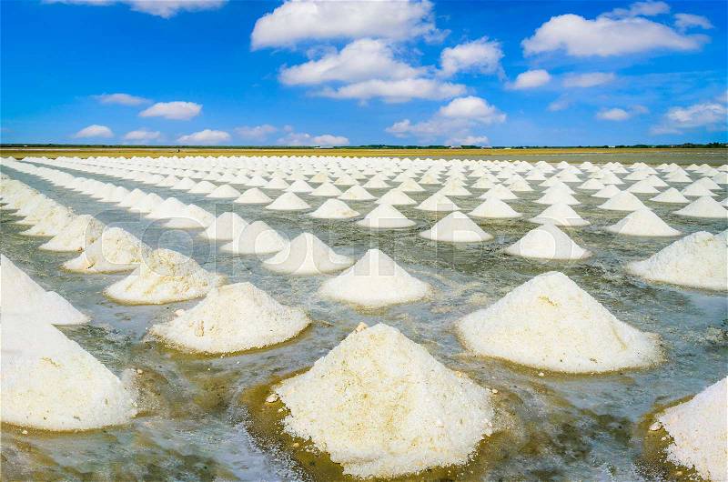 Sea salt fields with piled salt on blue sky background in Thailand, stock photo