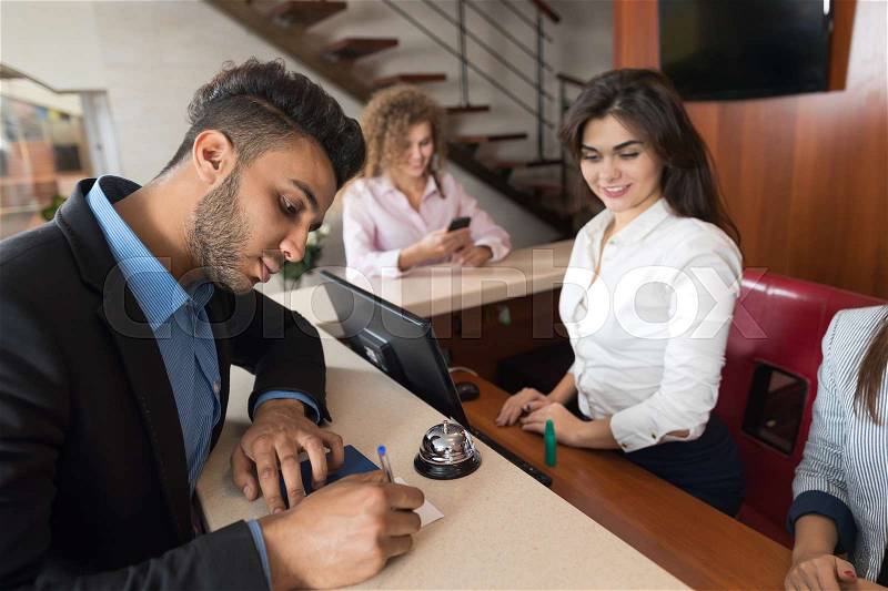 Business Man Arriving To Hotel Singing Document Meeting Woman Receptionist Room Registration At Reception Counter Checking In, stock photo