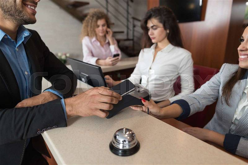 Business Man Arrive To Hotel Check In With Cell Phone Woman Receptionist Registration At Reception Counter, stock photo