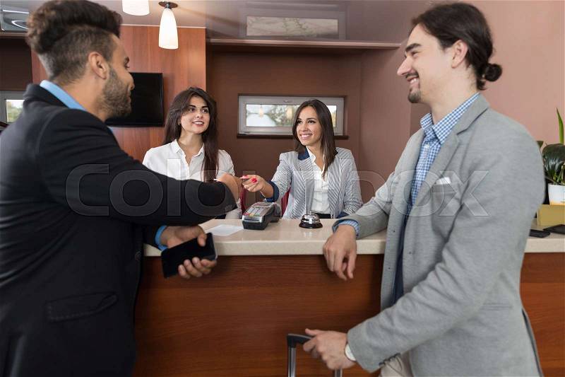 Two Business Man Arriving To Hotel Give Meeting Woman Receptionist Credit Card Pay Room Registration At Reception Counter Checking In, stock photo
