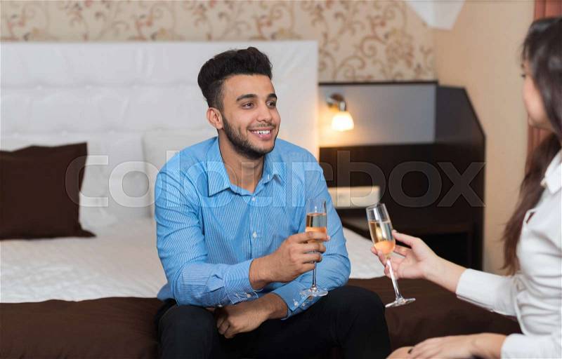Latin Businessman Sitting At Bed In Room With Businesswoman Drink Champange Business Man And Woman Arriving To Hotel, stock photo