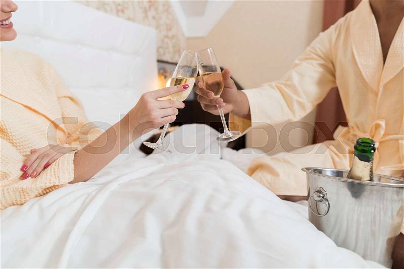 Young Couple Hold Glass Of Champagne Sitting Bed, Happy Smile Man And Woman Honeymoon Lovers In Bedroom, stock photo