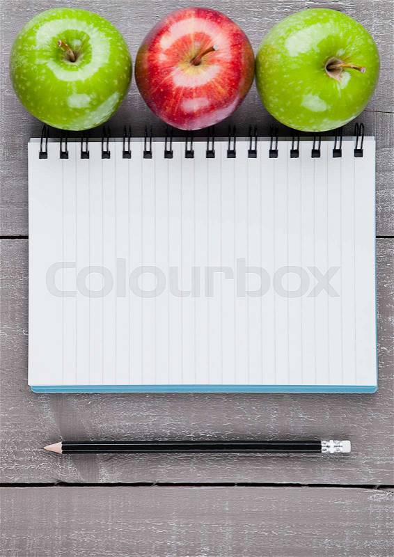 Writing pad with healthy apples as diet plan idea on wooden board, stock photo