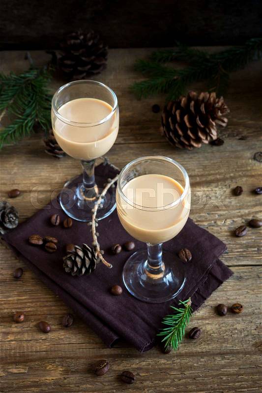 Irish cream coffee liqueur with coffee beans, Christmas decoration and cones over rustic wooden background - homemade festive Christmas alcoholic drink, stock photo