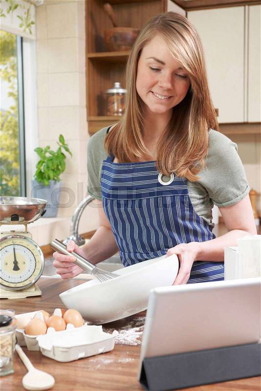 Woman Cooking And Following Recipe On Digital Tablet, stock photo