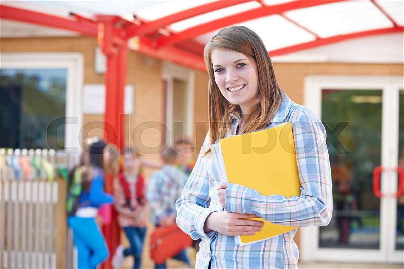 Portrait Of Teacher Standing In Playground With Folder, stock photo