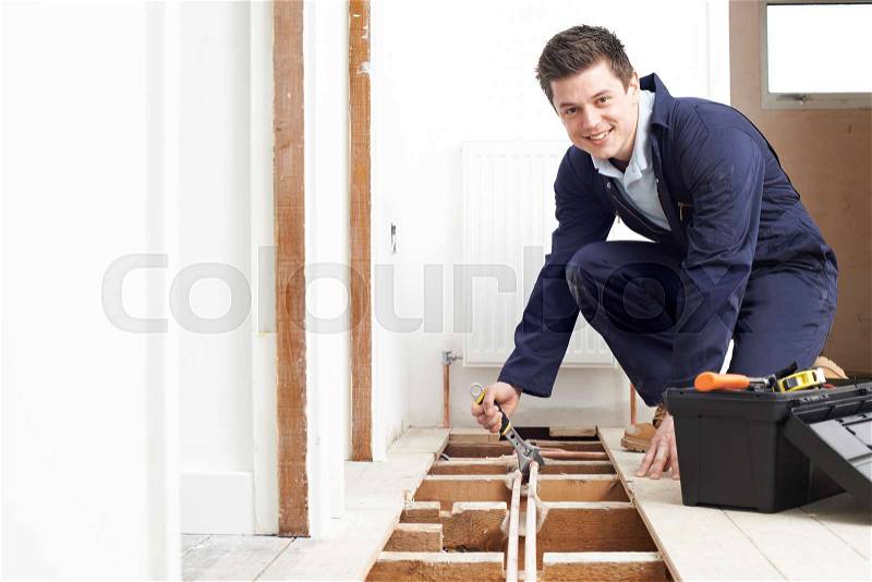 Plumber Fitting Central Heating System In House, stock photo
