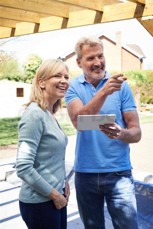 Mature Woman Looking At Design On Digital Tablet With Landscape Gardener, stock photo
