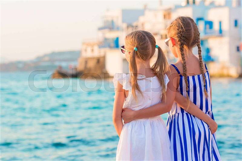 Back view of little kids at Little Venice the most popular tourist area on Mykonos island, Greece, stock photo