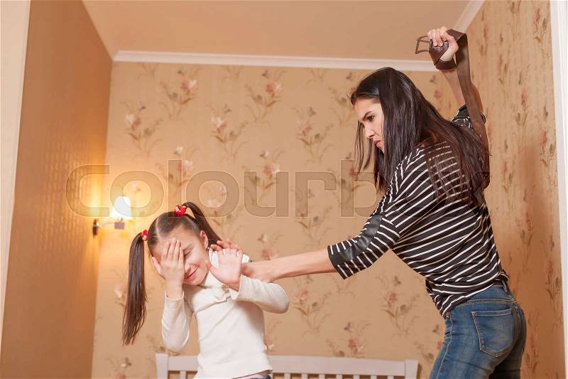 Strict mother hit her little daughter with belt, stock photo