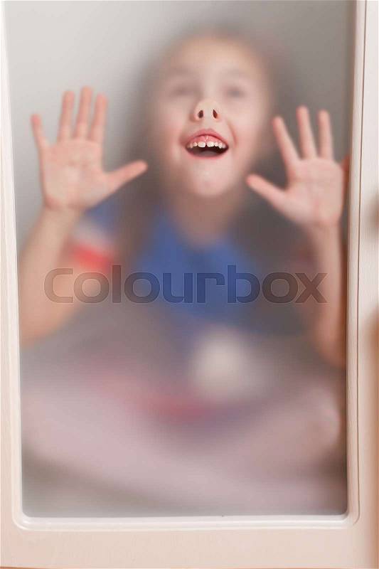 Kid leaning face to the glass and makes funny face, stock photo