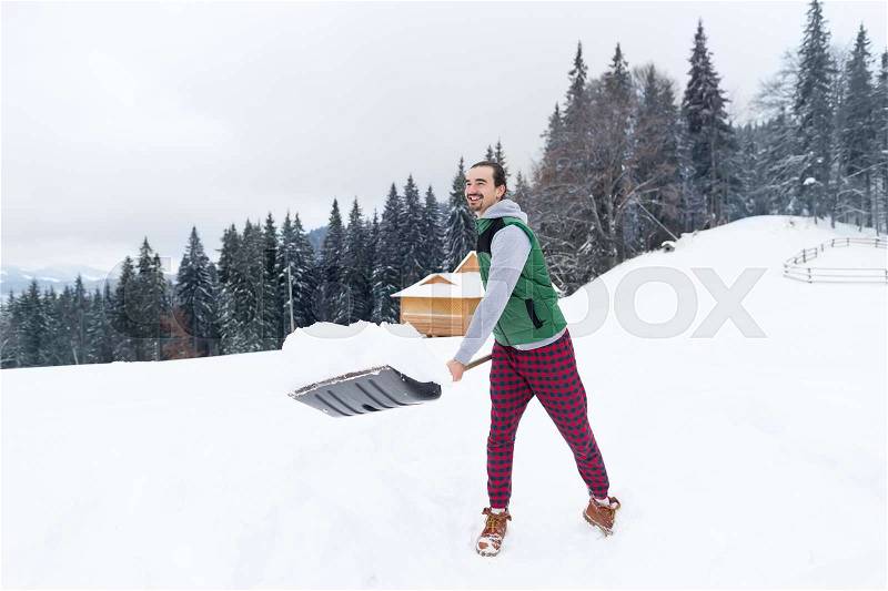 Young Man With Snow Shovel Snowy Village Wooden Country House Winter Resort Cottage Holiday Vacation, stock photo