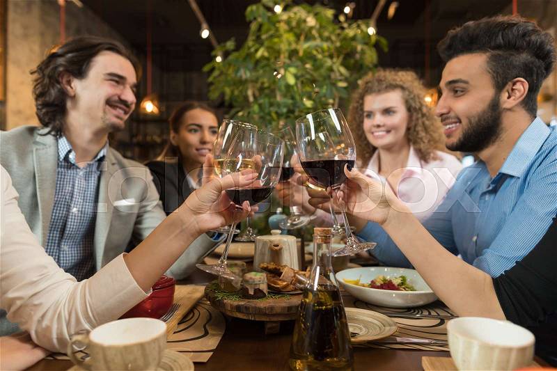 Young Business People Group Drink Wine Sitting Restaurant Table, Friends Hold Glasses Clink Toasting Smiling Mix Race Men Women, stock photo