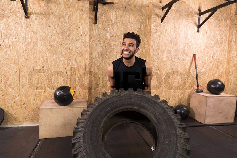 Sport Fitness Man Flipping Wheel Tire Crossfit Training, Young Healthy Guy Gym Interior, stock photo