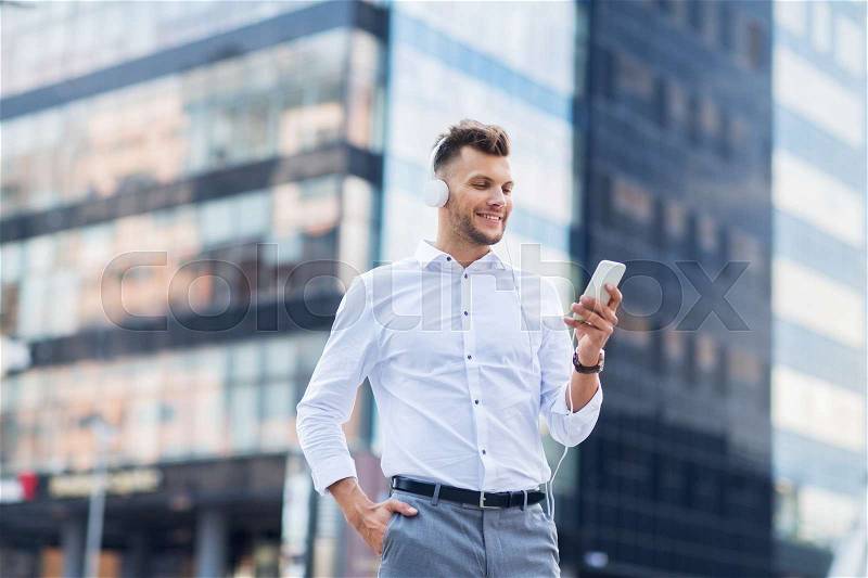 People, technology and lifestyle - happy young man with headphones and smartphone listening to music in city, stock photo