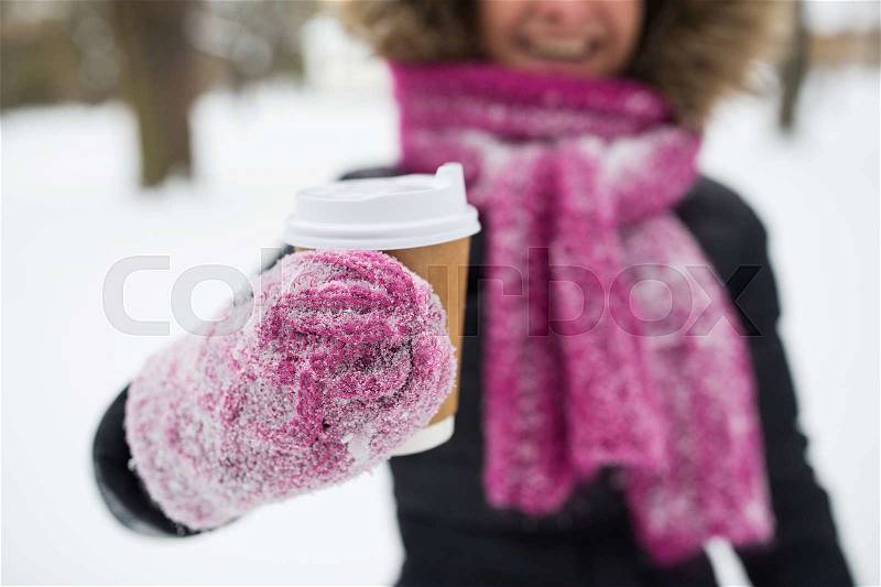 People, season, drinks and leisure concept - close up of woman hand with coffee cup outdoors in winter, stock photo