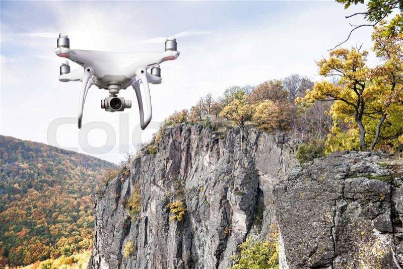 Hovering drone taking pictures of autumn nature. Colorful forest, rocky hill, stock photo