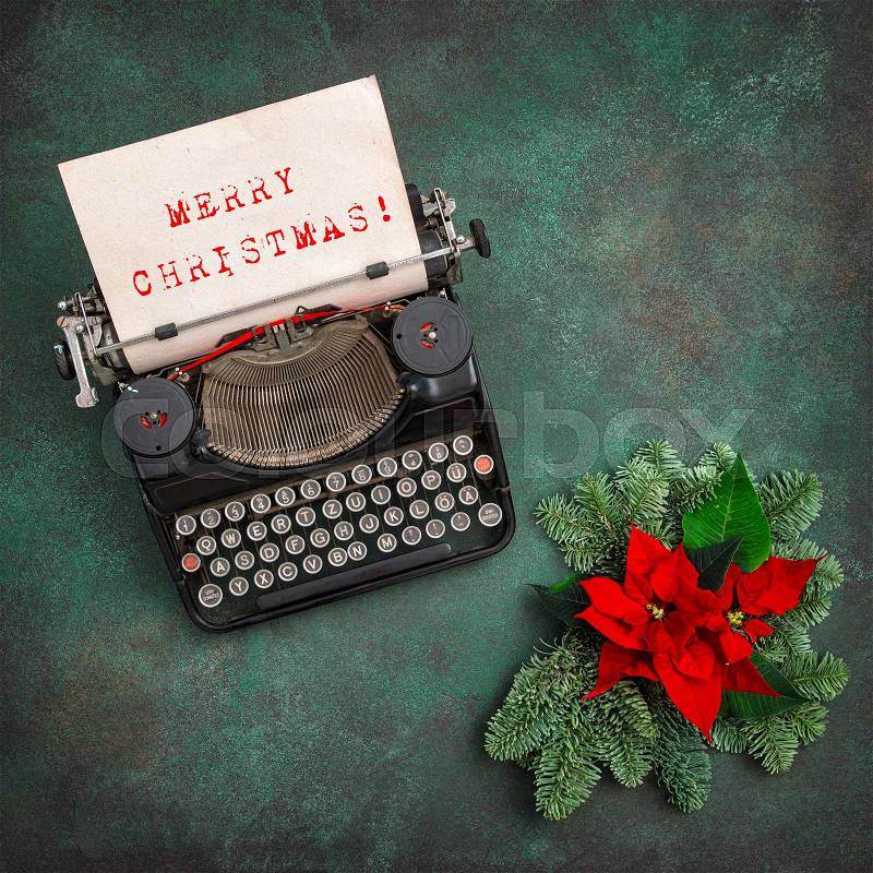 Vintage typewriter with Christmas decoration and red poinsettia flowers. Merry Christmas! Vintage style toned picture, stock photo