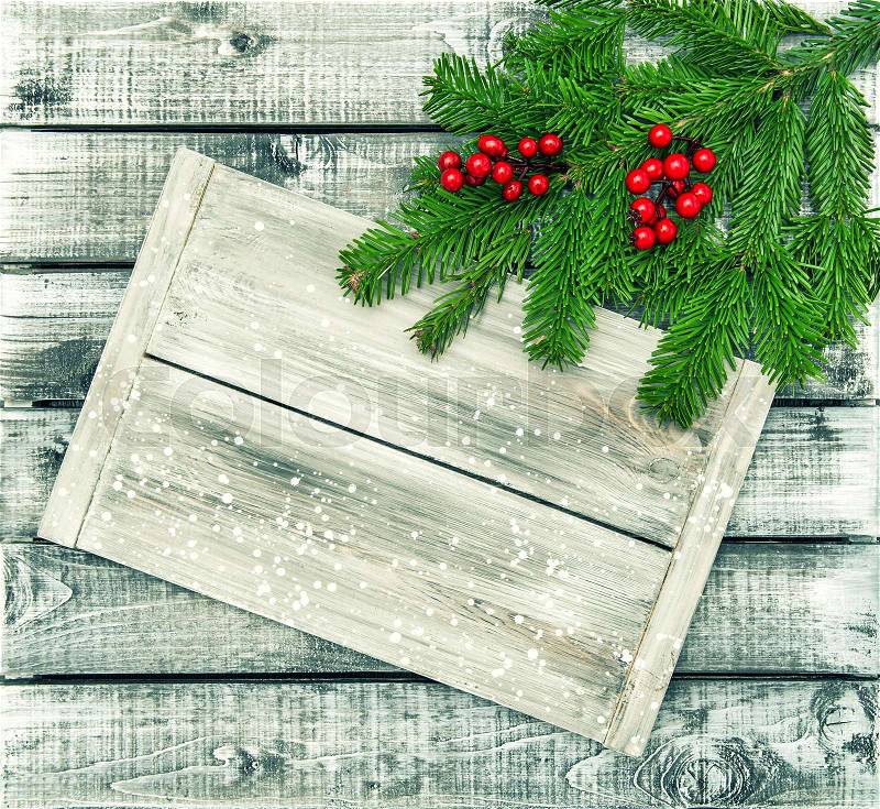 Christmas tree branches on rustic wooden background. Evergreen twigs with red berries decoration. Vintage style toned picture, stock photo