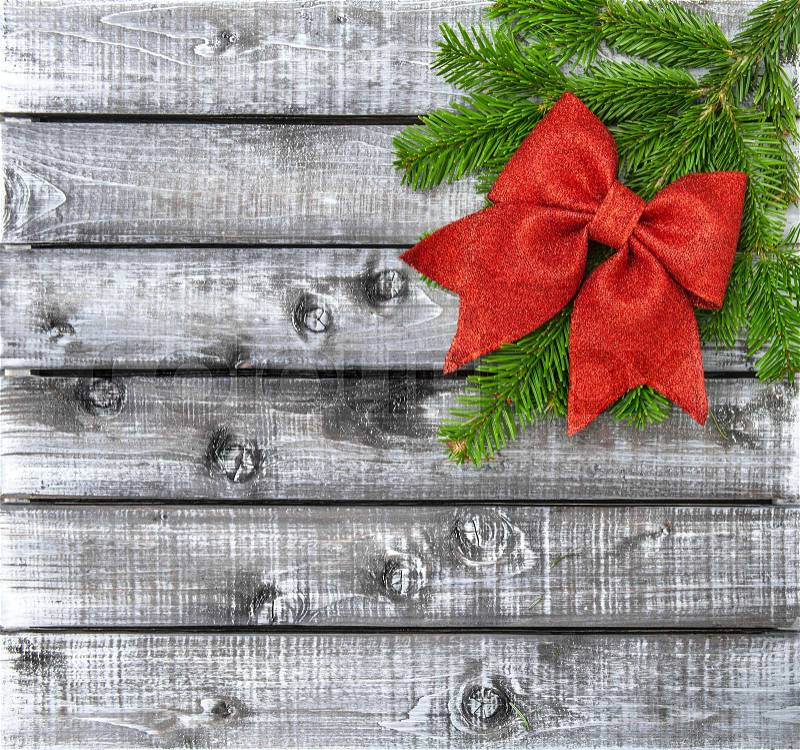 Christmas tree branches with red ribbon bow on rustic wooden background, stock photo