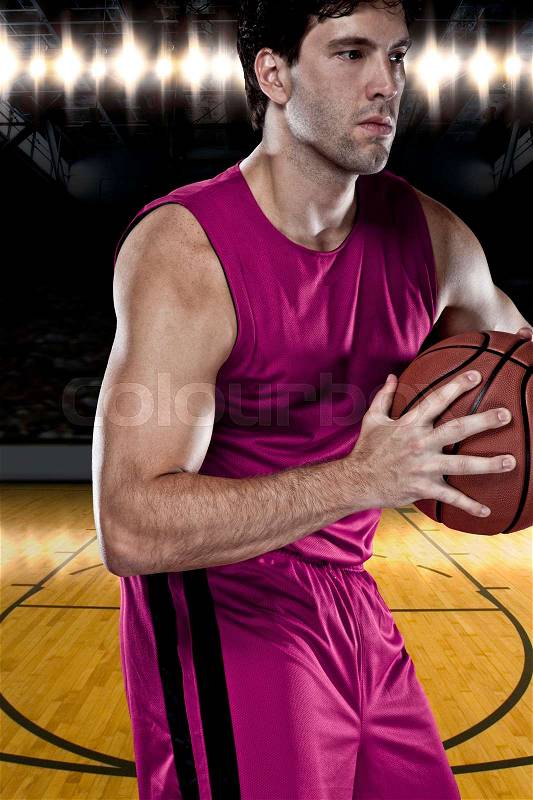 Basketball player on a pink uniform, on a basketball court, stock photo