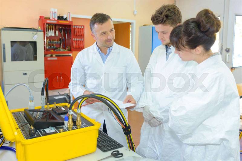 Students looking at electrical device, stock photo