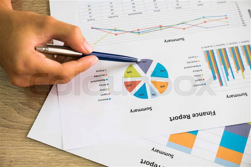 Closeup of male right hand holding pen points on colorful business graph in office top view, stock photo