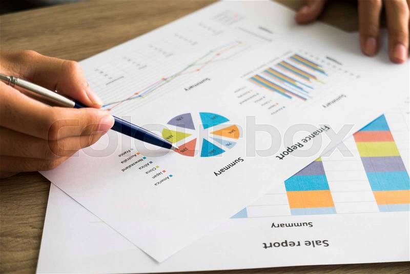 Closeup of male right hand holding pen points on colorful business graph in office, stock photo