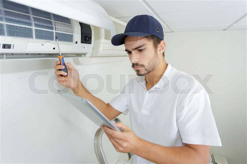 Young contractor working carefully and seriously at clients office, stock photo