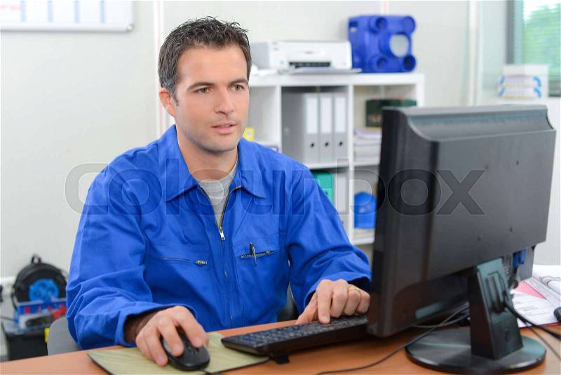 Man in overalls on computer, stock photo