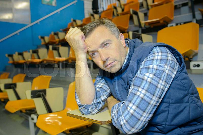 Man in auditorium looking fed up, stock photo