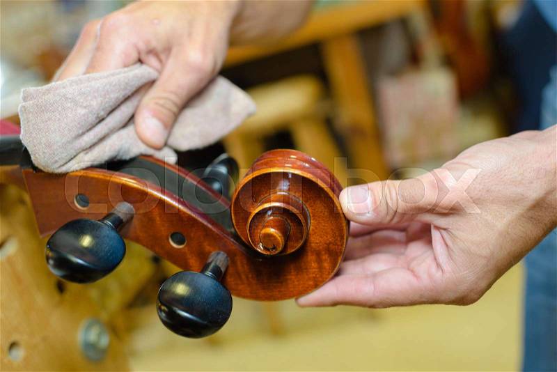 Hands polishing end of musical instrument, stock photo