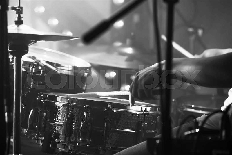 Black and white live music background, drummer plays with drumsticks on rock drum set. Closeup photo with soft selective focus, stock photo