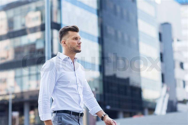 Lifestyle and people concept - young man walking along city street, stock photo